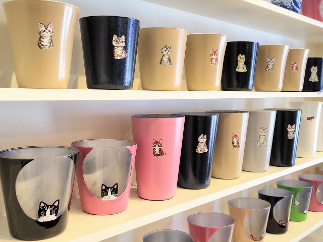 さまざまな猫の絵を手描きしたグラスが、工房鈴蘭の直営店の商品棚に並ぶ様子