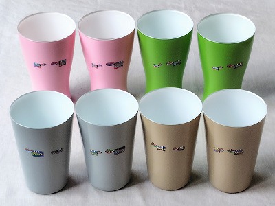ピンク、グリーン、グレー、ベージュのグラスに、色とりどりのカラーべこを手描きした商品を並べた様子