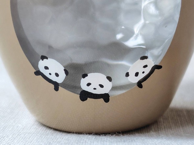 丸い窓の下に3頭のパンダを描いた、カフェオレカラーのお月見ミニグラス。現在店頭に並ぶ中で、男の子が提案してくれた案に最も近いデザイン。